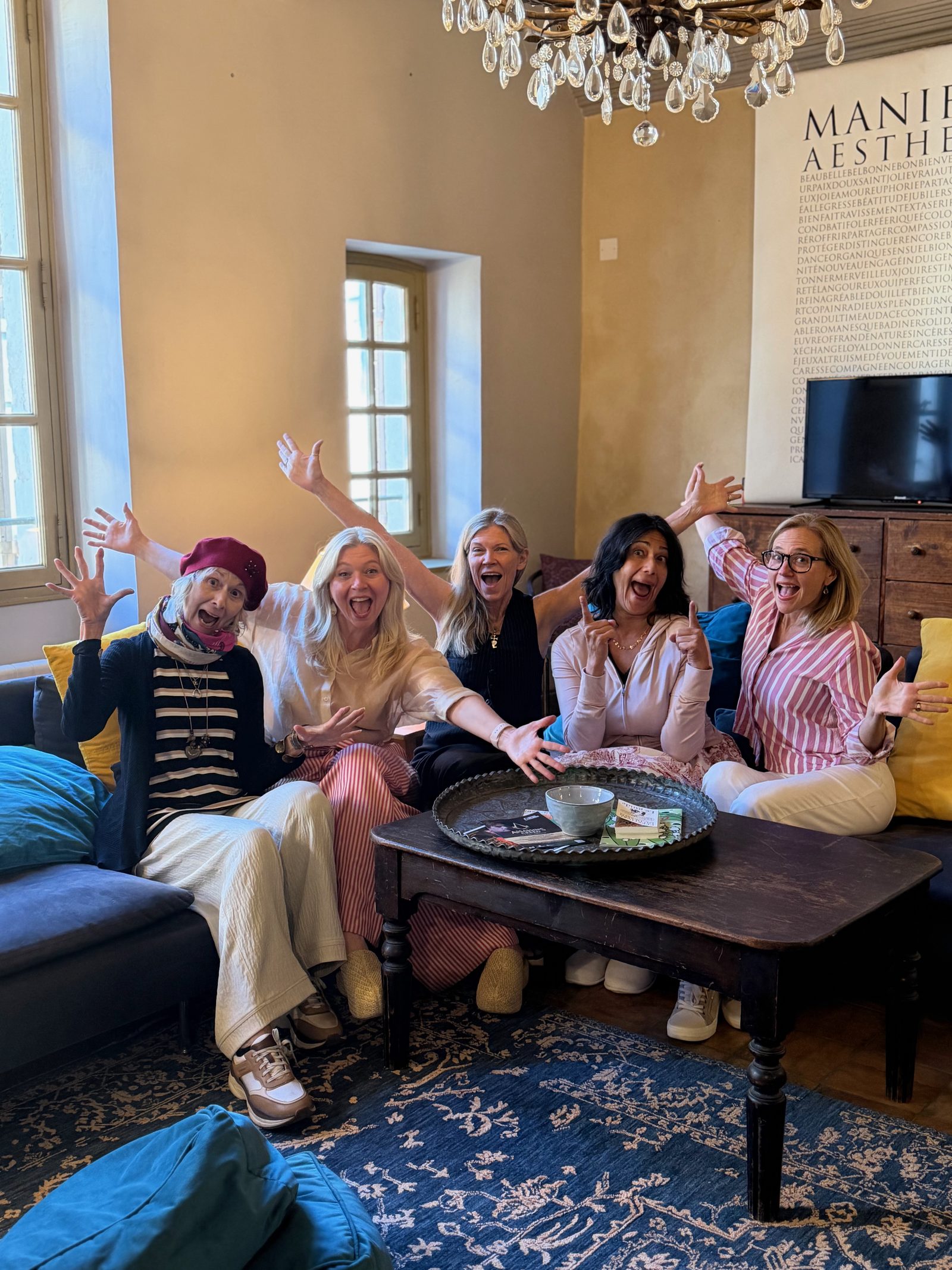 Five writers in a sun-filled room in Arles, arms raised in joy